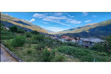 Scorcio di Giaglione affacciato sulla Val di Susa, tra orti verdi e montagne illuminate dal sole (foto: M. Caparello)